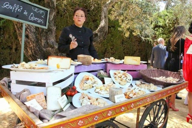 Buffet de quesos montado sobre un carro de madera en un evento al aire libre en Sevilla