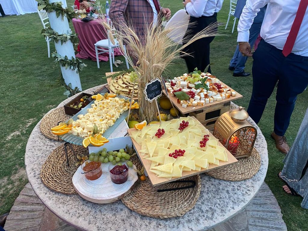 Mesa de picoteo con quesos, ibéricos y frutas montada en el jardín para el cóctel de una boda