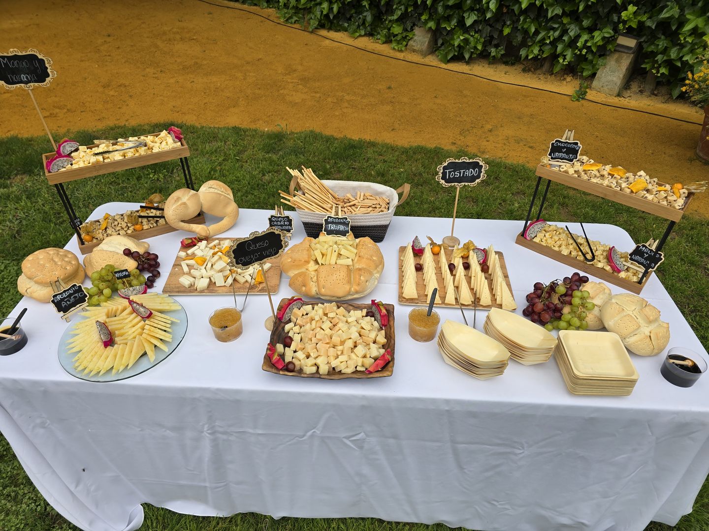 Mesa de quesos, ibéricos y aperitivos montada sobre el césped en un evento en Sevilla