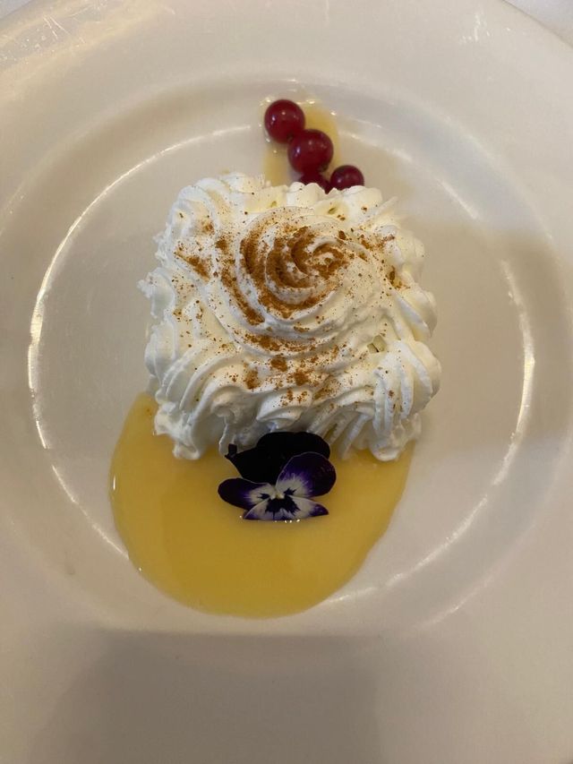Postre de merengue tostado con crema y flor comestible servido en un evento en Sevilla