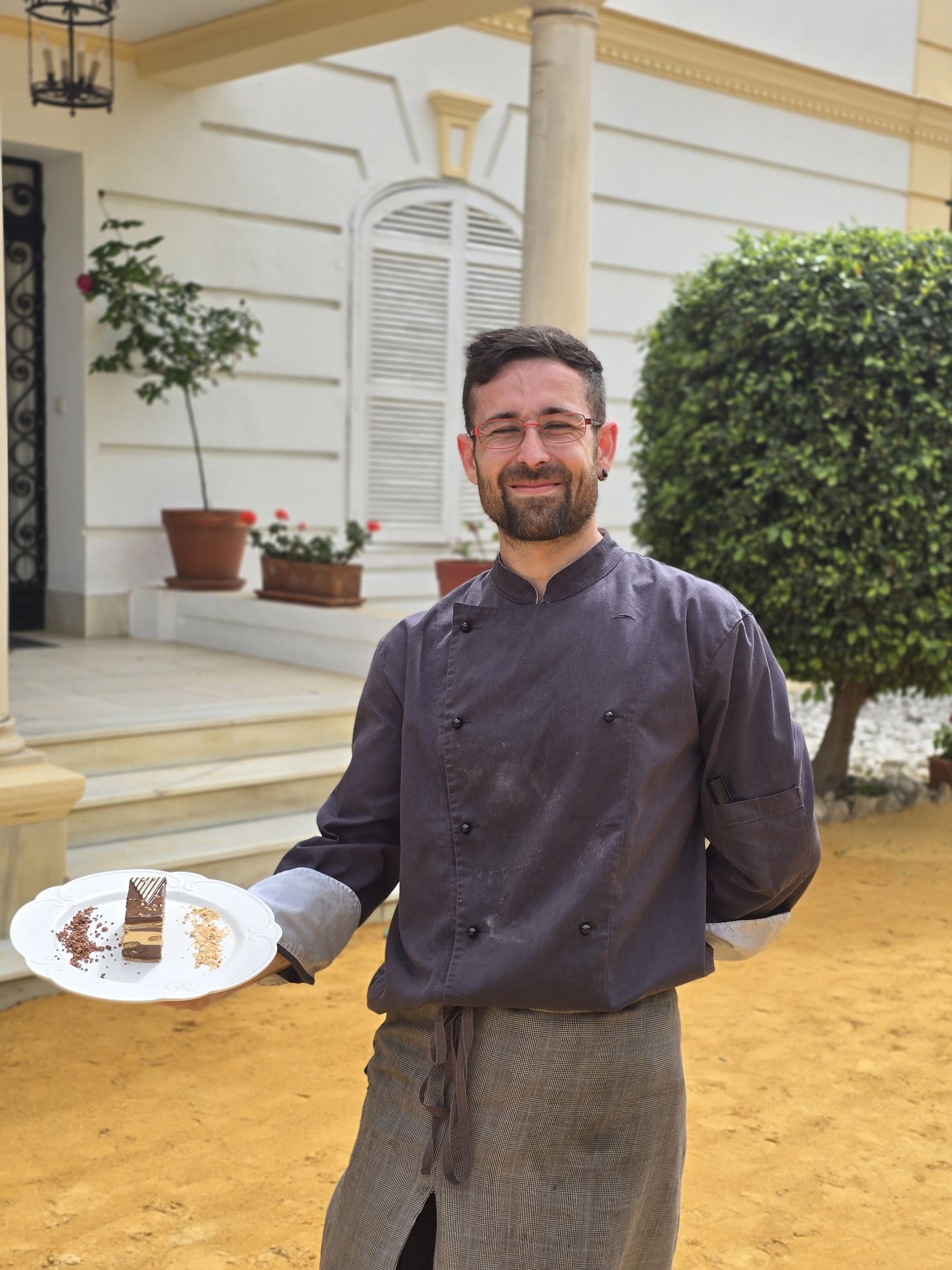 Integrante del equipo de Pablo Fernández Catering con un postre emplatado en el jardín